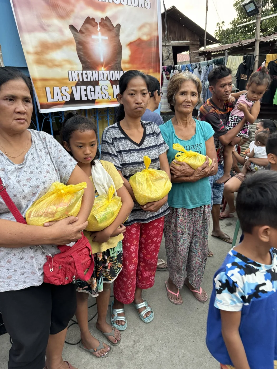Women and a child holding food-relief packages received during a community outreach